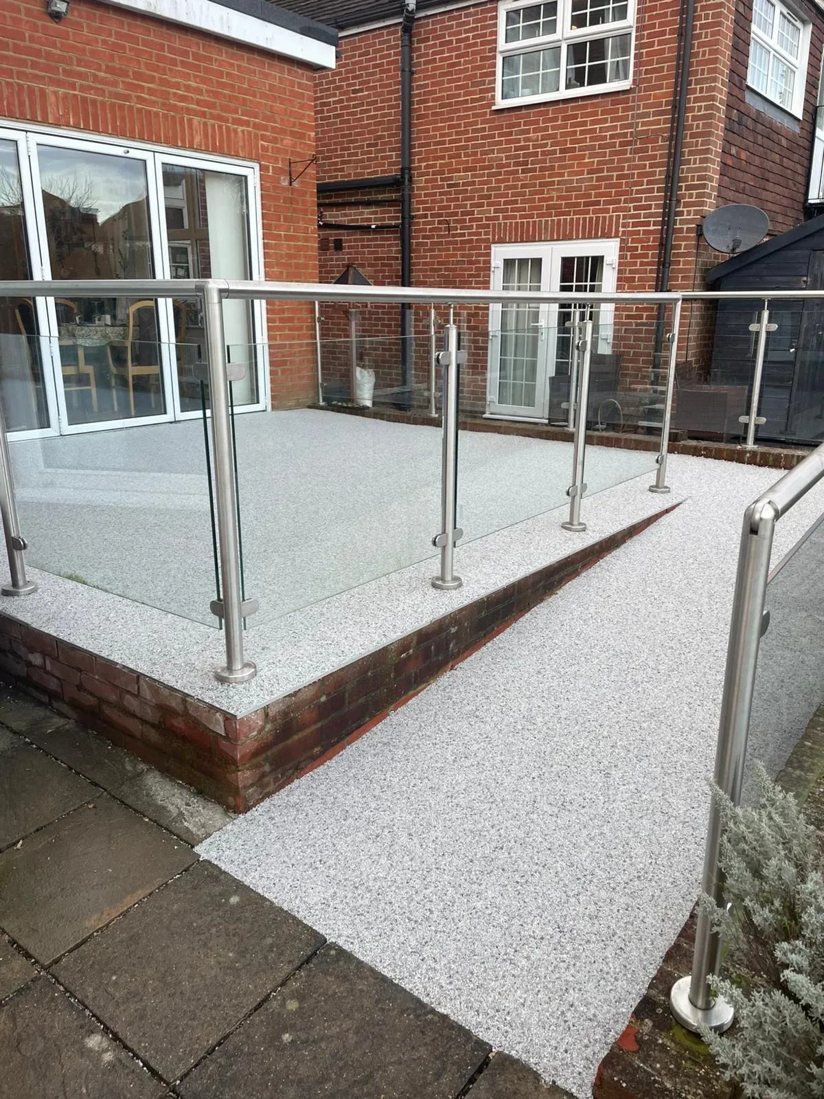 Modern resin patio and ramp installation with glass railings by Kent Paving & Resin LTD
