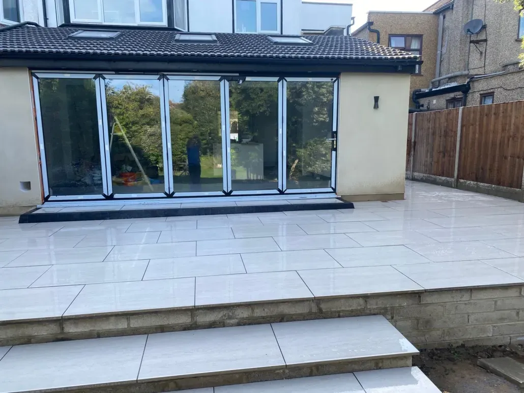 Newly installed modern patio and garden steps using large light grey paving slabs by bi-fold doors.