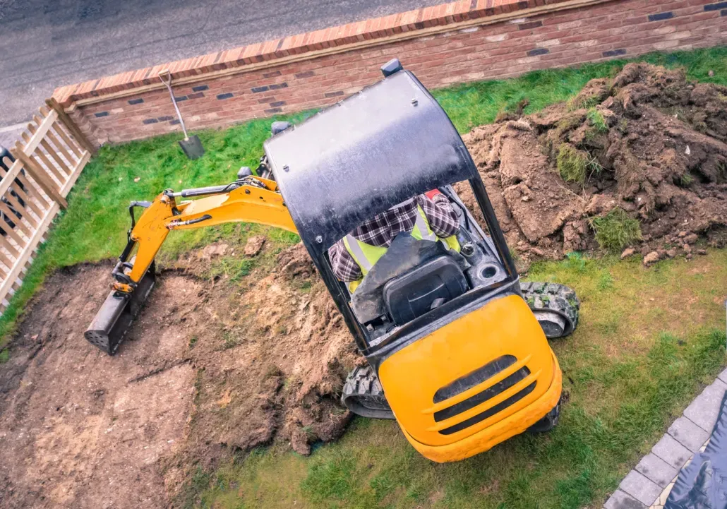 Small excavator digging earth during groundwork.