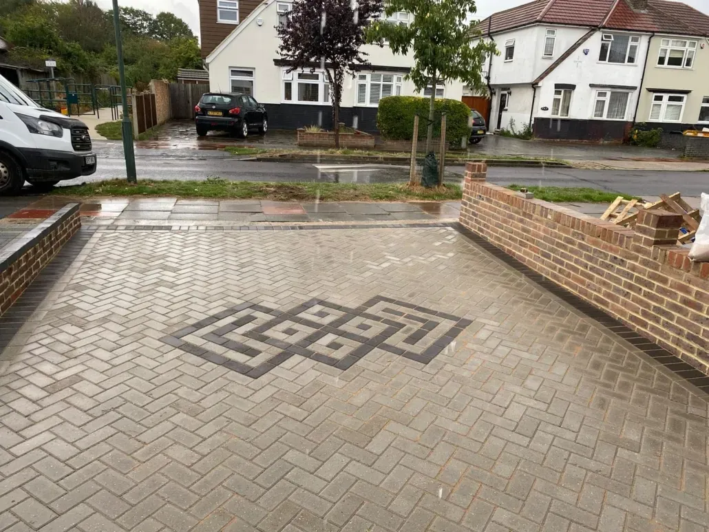 Block paving driveway with decorative pattern and brick wall in the foreground.